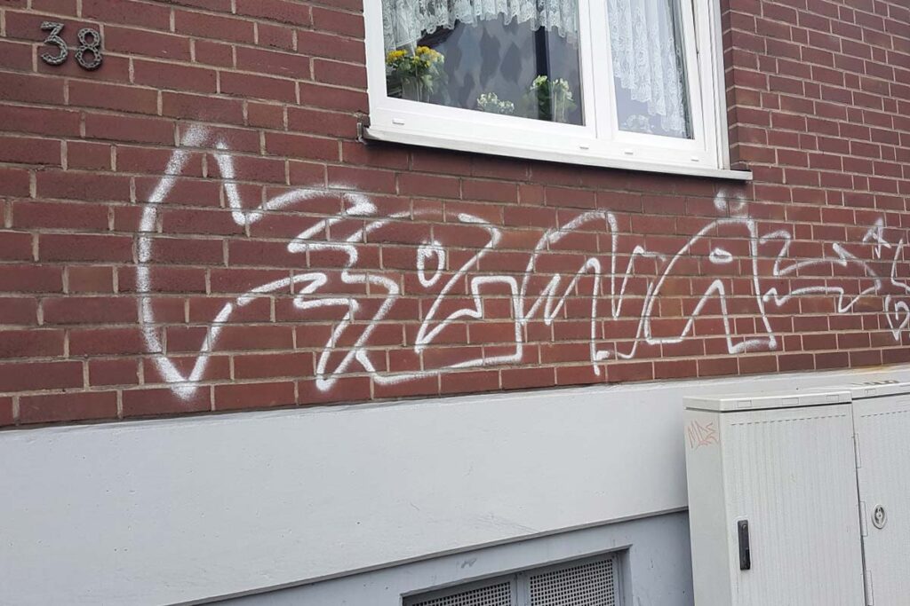 Mit Graffiti besprühte Backsteinwand vor der Reinigung – CleanTown24
